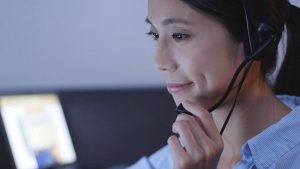 A woman wearing a headset, focused on her computer screen, while working.