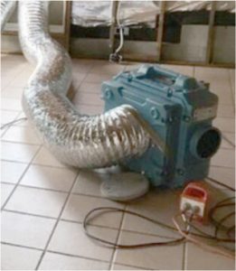 Metal ducting and fan on floor in industrial setting.