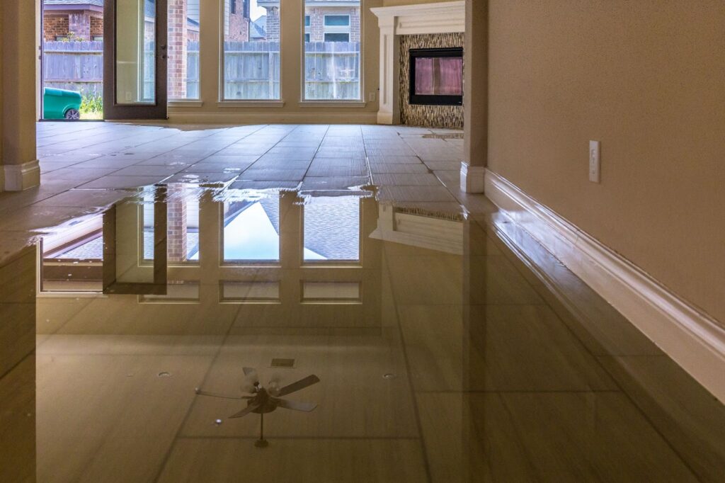Flooded home floor with ceiling fan, emphasizing need for restoration services and insurance coverage