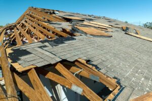 A damaged roof with shingles and wood, in need of wind damage repair.